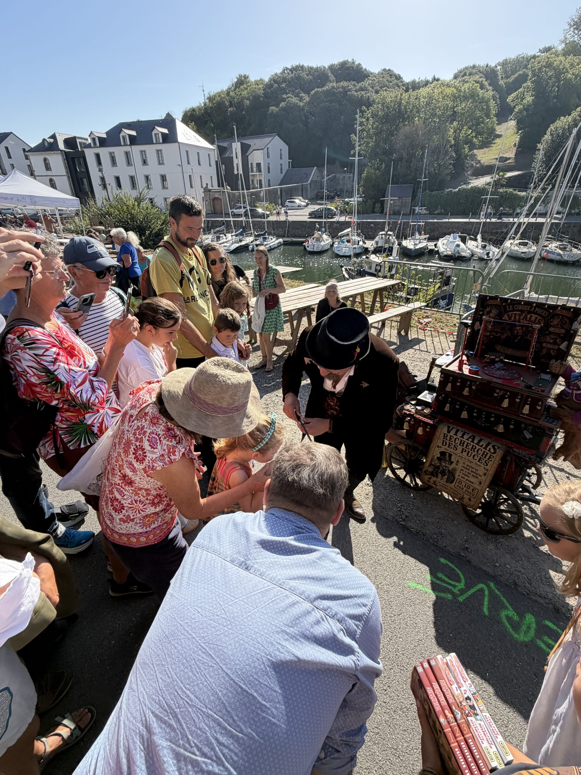 Public rassemblé au bord de l'eau autour de la roulotte du Cirque à Puces de Vitalis, un attroupement de curieux se forme à chaque halte